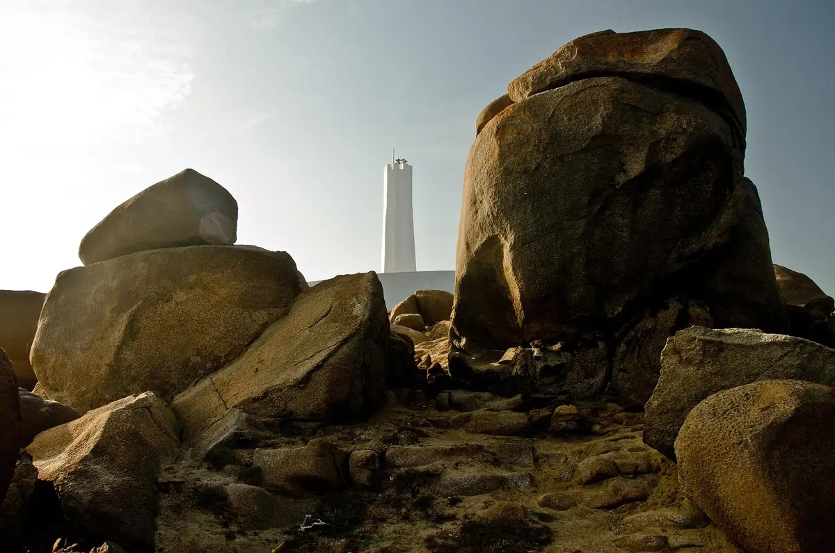 Farol branco da Pedra do Sal visto entre grandes rochedos de granito, em Parnaíba (PI)
